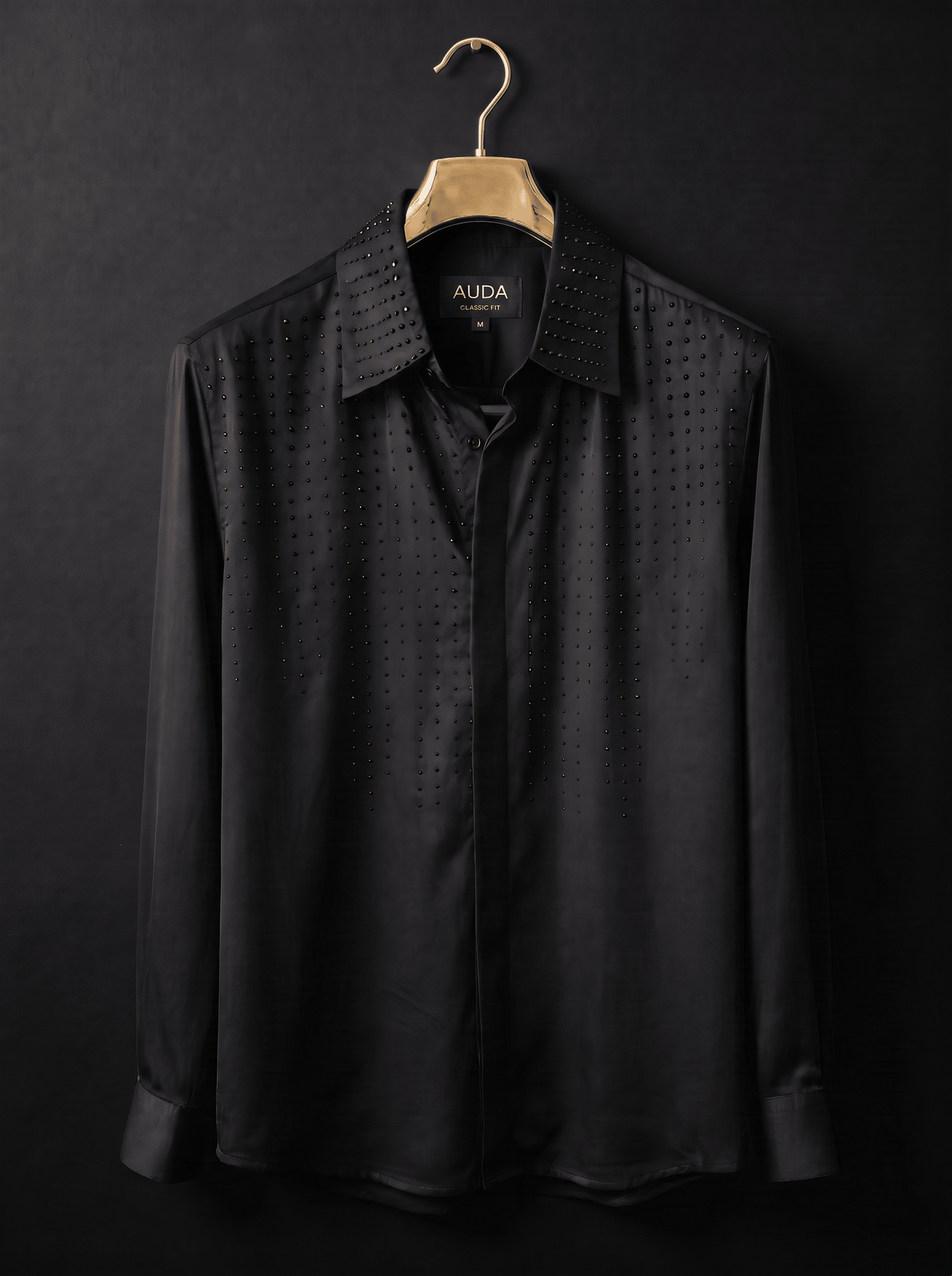 A black long-sleeve button-up shirt with a subtle perforated dot pattern and a studded collar, hanging on a gold hanger against a dark background. The brand name 'ALDA' is visible on the inner neck label.