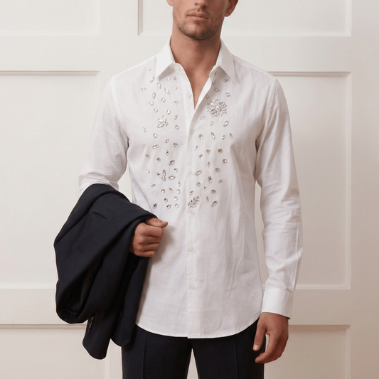 Man wearing a white embroidered shirt holding a black jacket against a white background