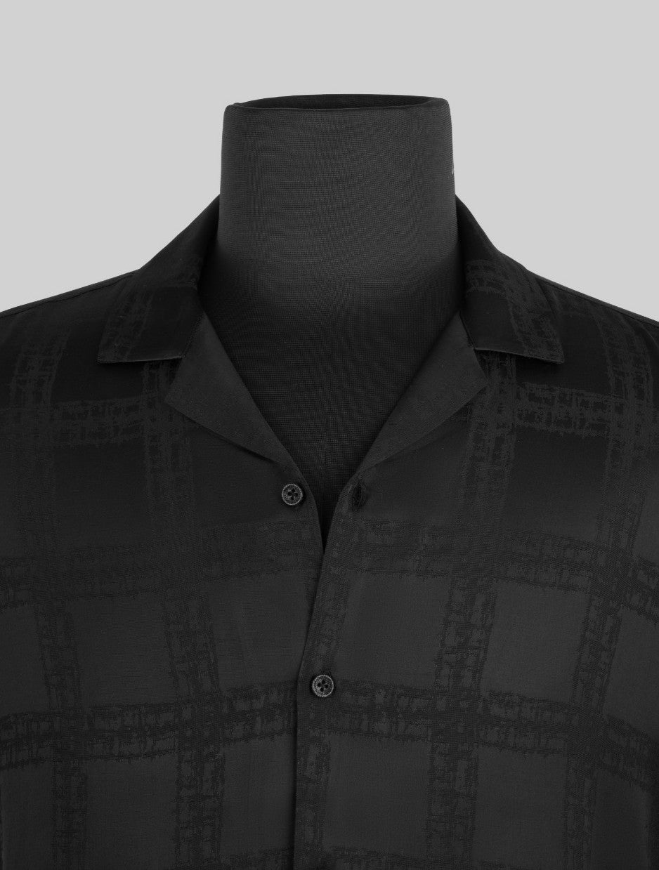 A close-up of a black button-up shirt with a subtle tonal grid pattern, displayed on a black mannequin torso against a light gray background.