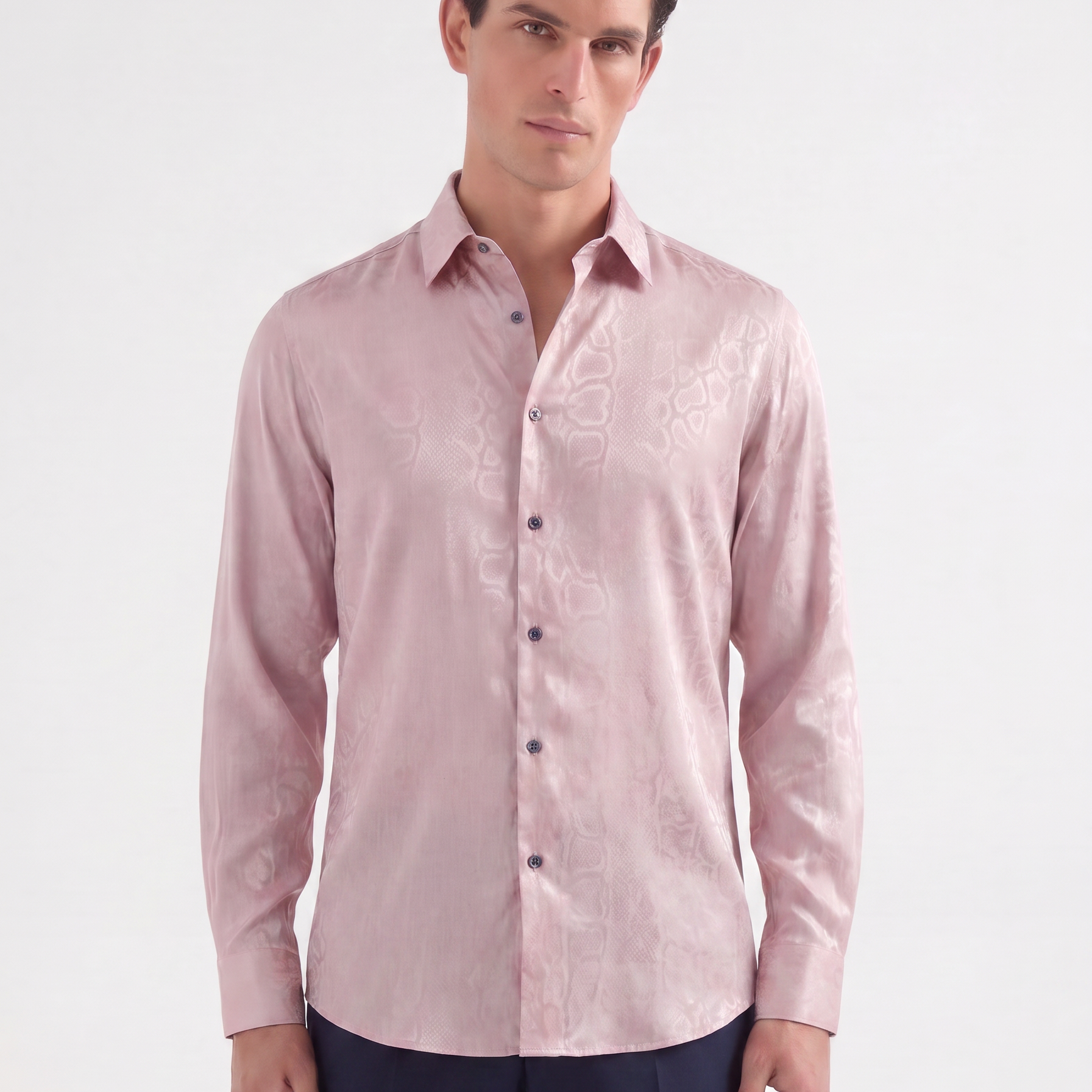 A man wearing a light pink long-sleeve button-up shirt with a subtle tonal floral jacquard pattern, paired with navy trousers, against a plain white studio background.