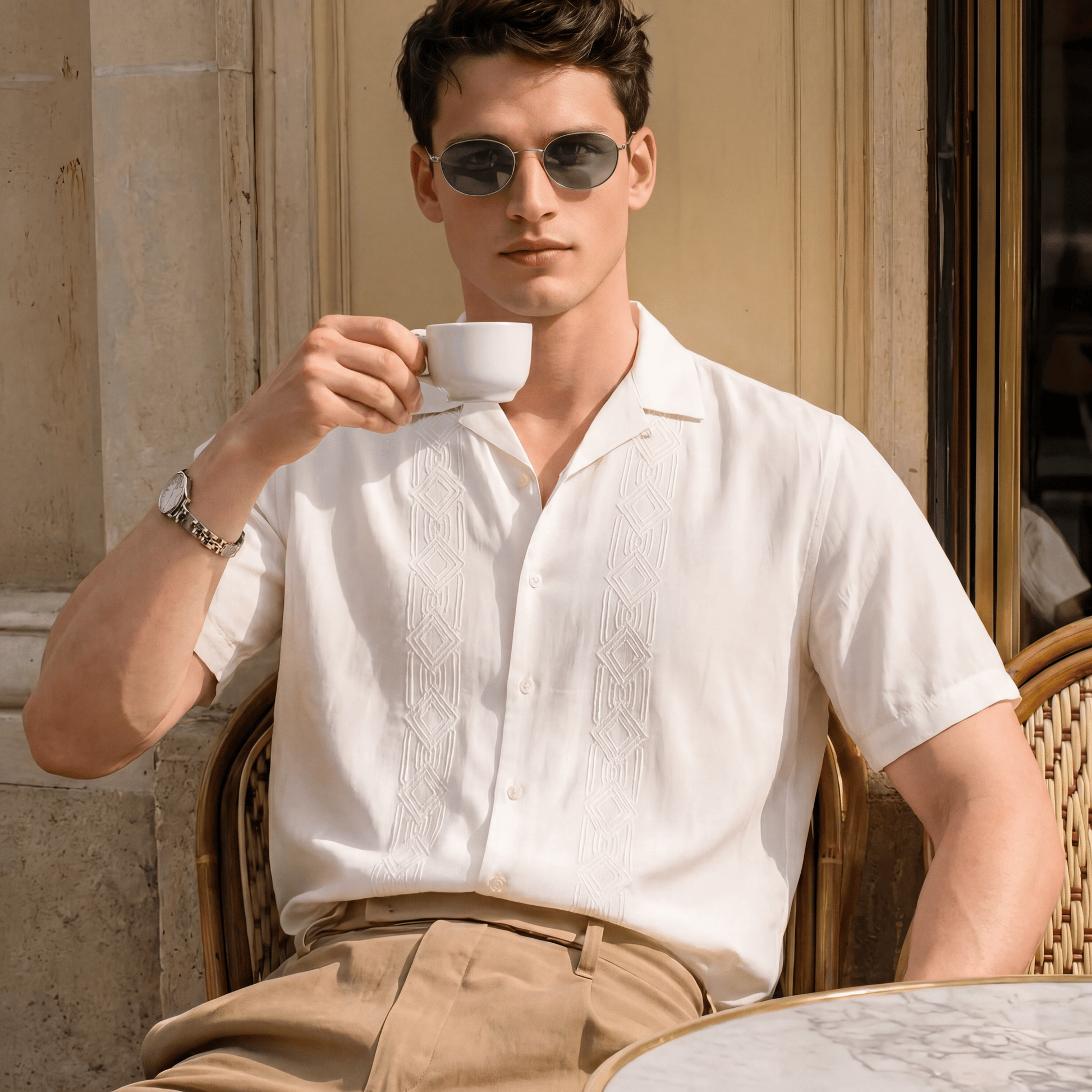 Man in outdoor setting wearing ivory Cuban collar shirt with beige trousers