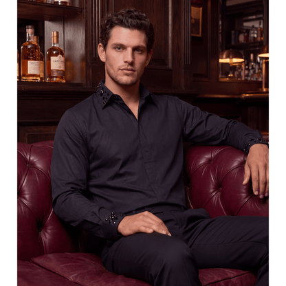 Man wearing black rhinestone button-up shirt in upscale lounge setting