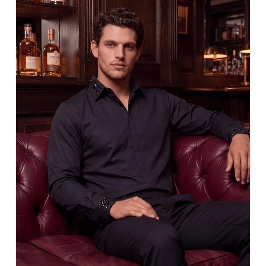 Man wearing black rhinestone button-up shirt in upscale lounge setting