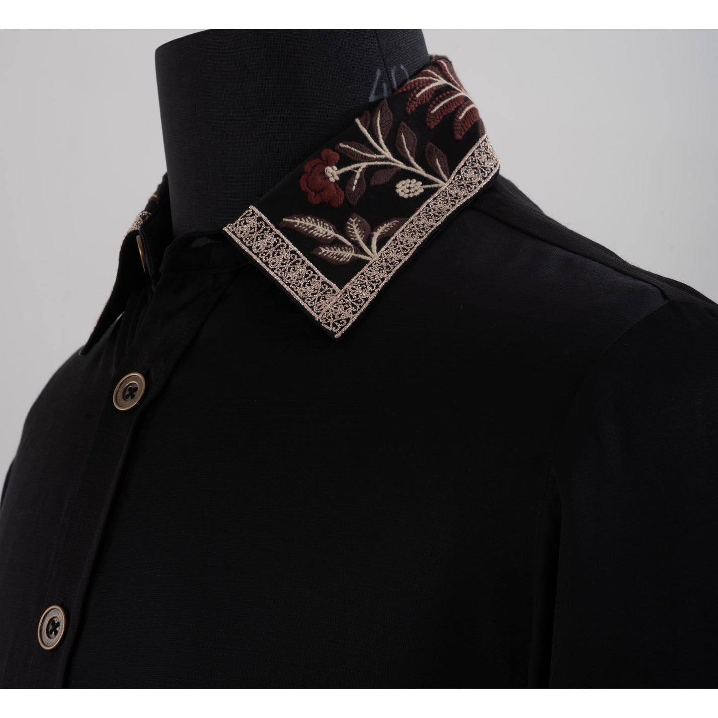 Close-up of black shirt collar featuring brown beige floral embroidery and lace trim