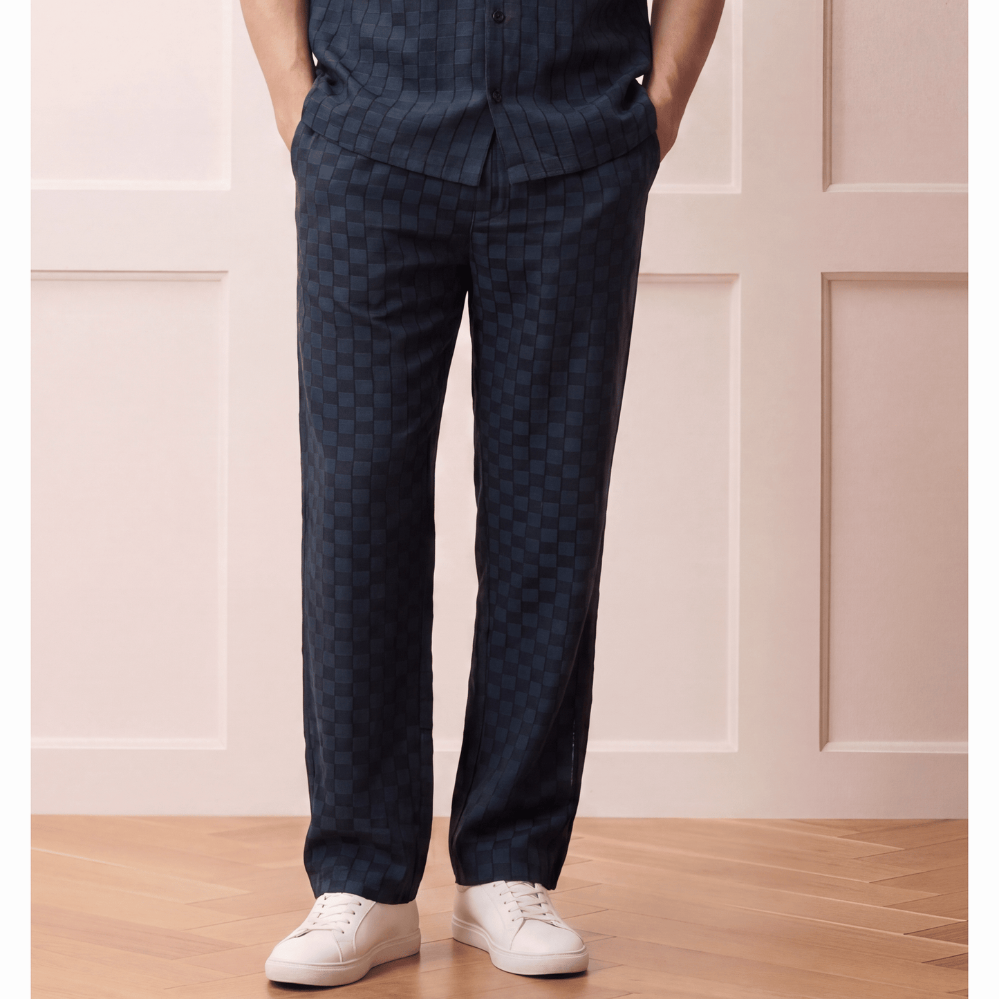 Relaxed dark navy check-patterned trousers with hybrid waistband worn by model in casual-luxury outfit
