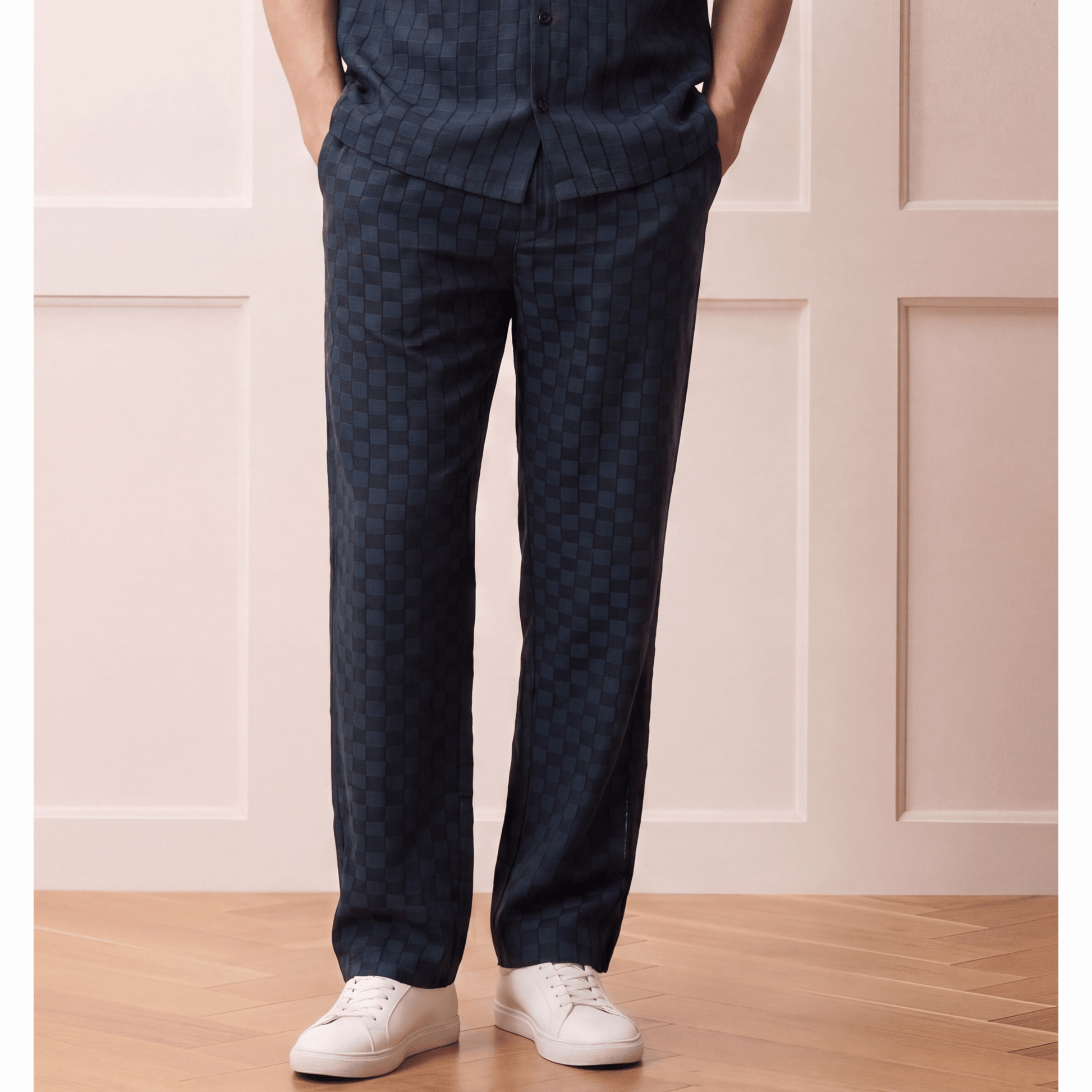 Relaxed dark navy check-patterned trousers with hybrid waistband worn by model in casual-luxury outfit